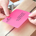A person's hand using a Lavex fluorescent pink mailing label.