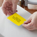 A person's hands using a Lavex yellow thermal transfer label on a box.