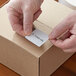 A hand using a white Lavex sticker to label a box.