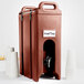 A brown plastic Cambro insulated beverage dispenser with a black faucet and cups.