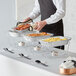 A man using Choice disposable chafing dishes to serve food on a table.