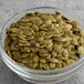 A bowl of Bob's Red Mill Organic Raw Pumpkin Seeds on a table.