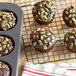 A chocolate muffin in a muffin tin with Bob's Red Mill Organic Raw Pumpkin Seeds on top.