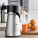 A Galaxy CJ180 electric citrus juicer on a counter next to a bowl of oranges.