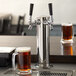 A glass of beer next to an Assure 190DBLETOWER 2 tap tower.