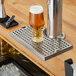 A Regency stainless steel beer drip tray on a counter with a beer glass on it.