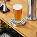A glass of beer on a stainless steel Regency surface mount drip tray.