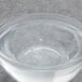 A clear glass bowl of clear liquid over a bowl of water with bubbles.