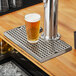 A glass of beer on a Regency stainless steel beer drip tray next to a beer tap.
