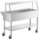 A silver stainless steel ServIt cold food table with angled glass sneeze guard and casters.