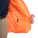 The hand of a person holding a pocket of an orange Cordova Cor-Brite safety vest.