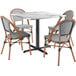 A Lancaster Table & Seating Versilla table with four French bistro chairs on an outdoor patio.