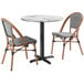 A Lancaster Table & Seating Versilla round table with two French bistro chairs.