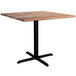 A Lancaster Table & Seating square wooden table with a black base.