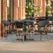 A Lancaster Table & Seating Paladina table with black chairs on a patio.