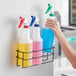 A person using a Lavex 3 compartment wall-mount holder for spray bottles.
