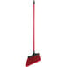 A red broom with a long black handle.