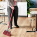A man using a Lavex angled broom with a red flag to sweep the floor.