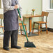 A person sweeping the floor with a Lavex green angled broom.