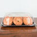 A Sabert plastic catering tray with a high dome lid holding bagels.