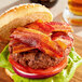 A bacon sandwich with lettuce and a burger patty on a bun.
