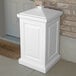 A white rectangular Mayne outdoor storage bin with a square top next to a door.