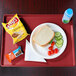 A red Cambro dietary tray holding a plate of food with a sandwich, tomatoes, and a bottle of water.
