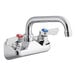 A Regency chrome wall mount faucet with a silver swing spout and red and blue knobs.
