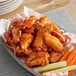 A plate of chicken wings with carrot and celery sticks served with Sauce Craft Hot Honey Sauce.