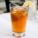A Libbey rim tempered mixing glass of iced tea with a lemon slice.