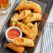 A plate of Gourmet Egg Roll Co. pizza egg rolls with red sauce.