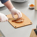 A person cutting meat on a Mercer composite cutting board.