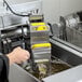A person using the VITO VM Portable Fryer Oil Filter System on a counter.