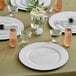 A table set with white Choice charger plates and glasses.