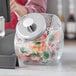 A Choice glass penny candy jar with a silver lid on a counter full of lollipops and candy.
