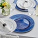 A table set with Choice royal blue beaded rim charger plates and silverware.