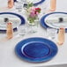 A table set with Choice royal blue charger plates and glasses with flowers in a glass jar.