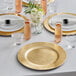 A table set with Choice gold charger plates and glasses with flowers on a table.