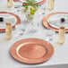 A table set with Choice rose gold charger plates, glasses, and a vase of flowers.