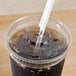 A Dart clear plastic lid with a straw slot on a plastic cup with a straw in it.