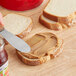 A person spreading Jif Creamy Peanut Butter on a slice of bread with a knife.