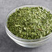 A bowl of McCormick Culinary Freeze-Dried Cilantro on a table.
