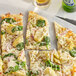 A slice of pizza with cheese and vegetables on a white surface with McCormick Culinary Mediterranean Oregano.