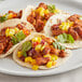 A plate of three chicken tacos with mango salsa on the table.