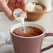 A person pouring International Delight creamer into a cup of coffee.