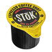 A yellow and black Stok Espresso Coffee Shot container on a table.