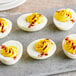 A deviled egg with yellow and red paprika toppings.