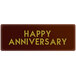 A rectangular brown Chocolatree chocolate decoration with yellow and gold text that reads "Happy Anniversary"