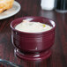 A cranberry Cambro bowl of soup on a table.