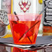 A Fineline Savvi Serve neon red hard plastic tumbler with a black straw in a red drink.